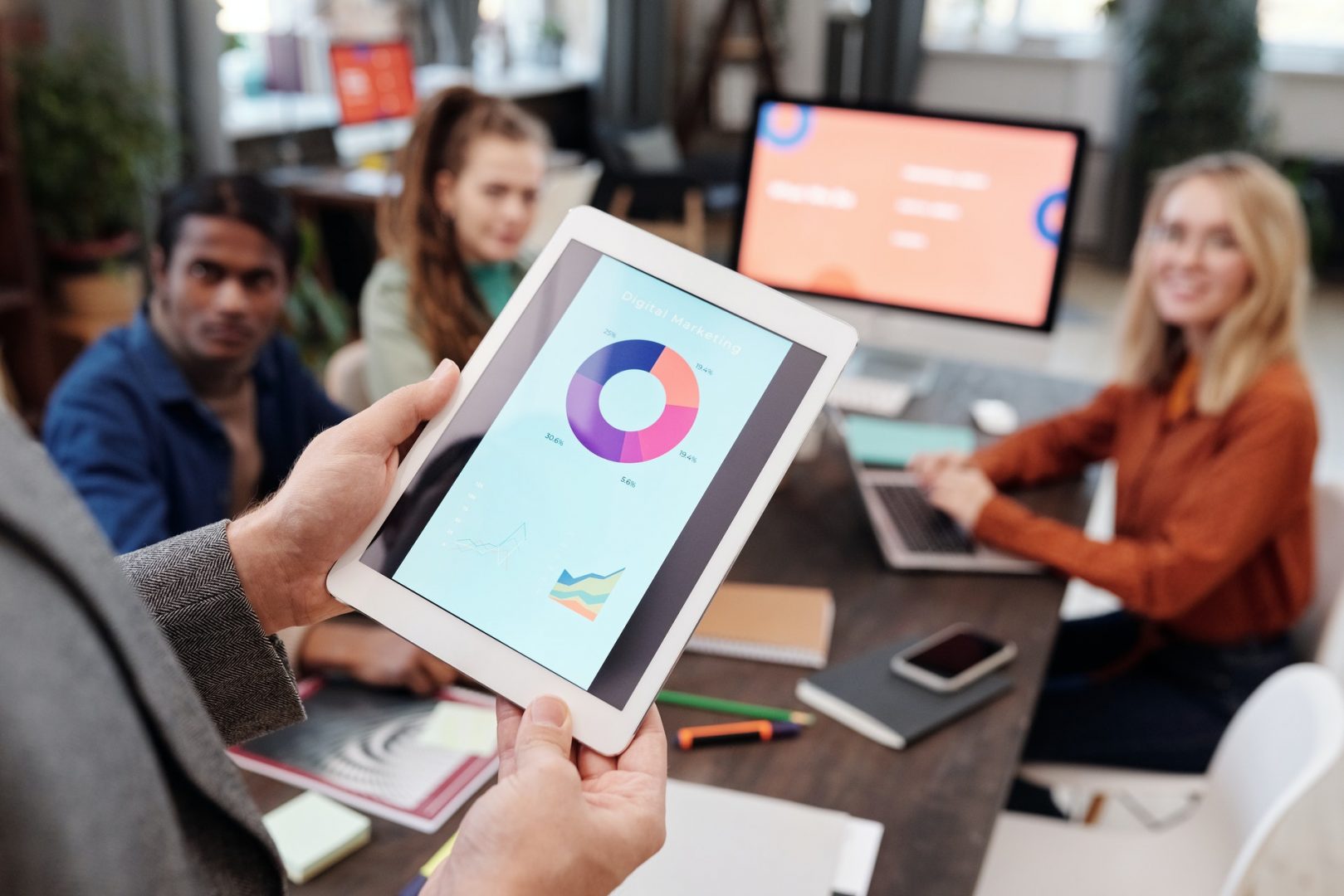 Group of people from a Digital Marketing Agency gathered around a table, someone is holding up a chart chart in the foreground